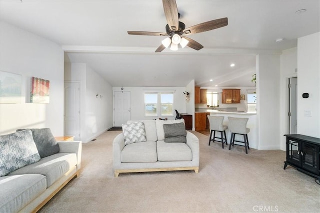 living room featuring a ceiling fan, light carpet, vaulted ceiling with beams, and baseboards