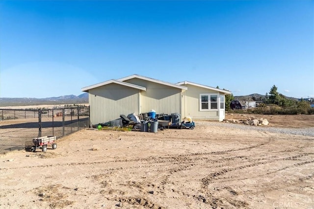 exterior space featuring a rural view, fence, and a mountain view