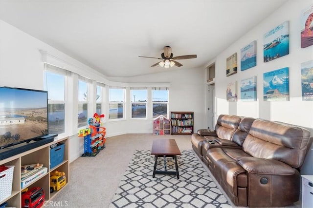 living area with vaulted ceiling, a ceiling fan, and light colored carpet