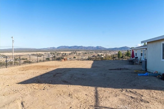 view of yard with a rural view, fence, and a mountain view