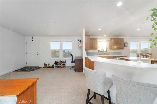 kitchen featuring light carpet, light countertops, a kitchen bar, a sink, and recessed lighting