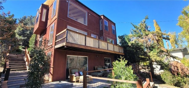 rear view of property with a balcony and stairs