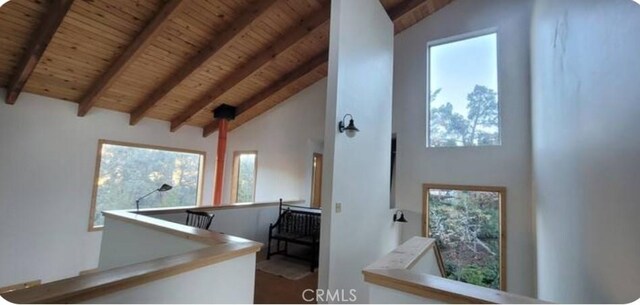 corridor featuring wood ceiling, beamed ceiling, and an upstairs landing