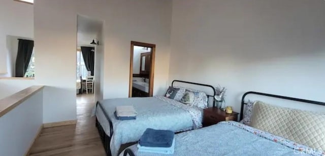 bedroom featuring a towering ceiling, baseboards, and wood finished floors