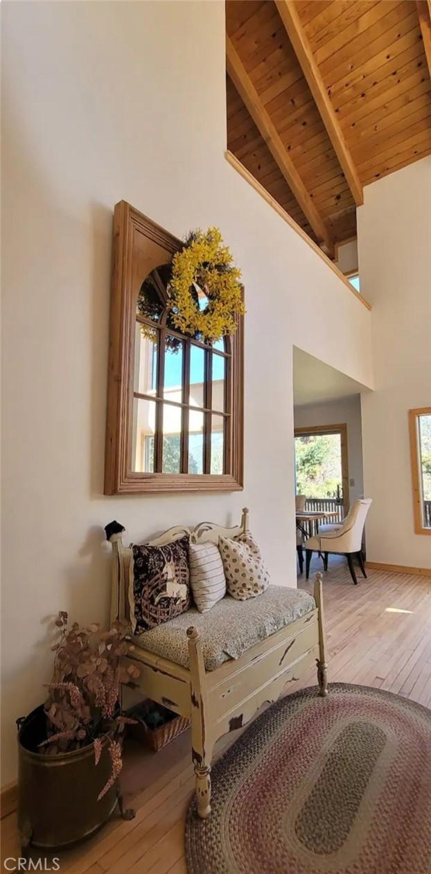 sitting room with high vaulted ceiling, wood ceiling, beam ceiling, and wood finished floors