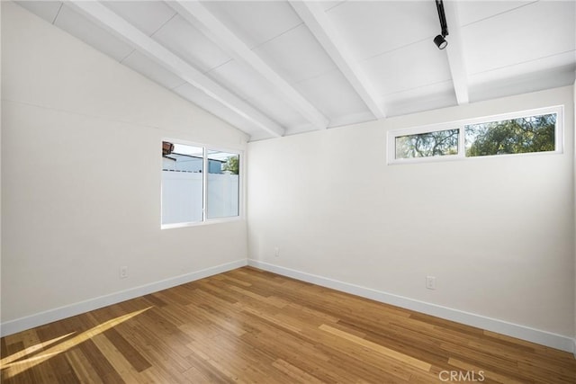 unfurnished room featuring lofted ceiling with beams, wood finished floors, and baseboards