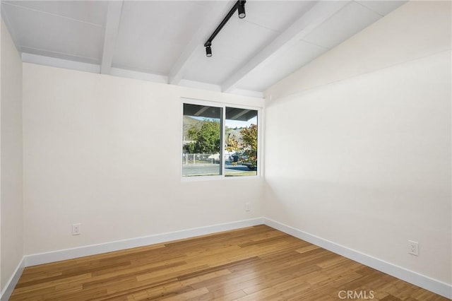 spare room with rail lighting, vaulted ceiling with beams, baseboards, and wood finished floors