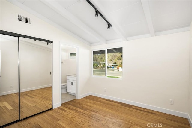 unfurnished bedroom featuring lofted ceiling with beams, light wood-style flooring, visible vents, and baseboards