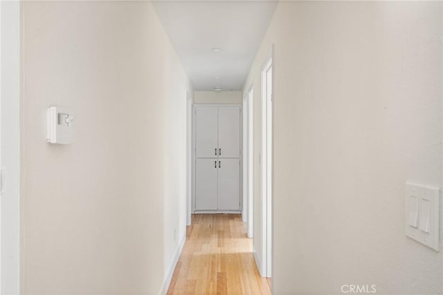 hall featuring light wood-style flooring and baseboards