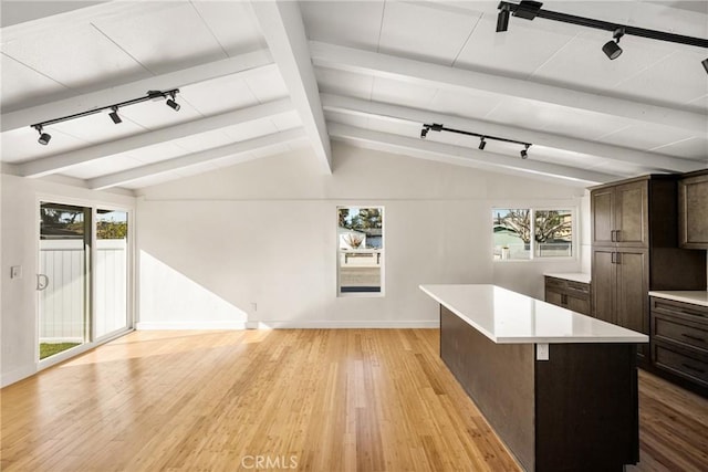 kitchen featuring vaulted ceiling with beams, light wood-style flooring, a kitchen island, and light countertops