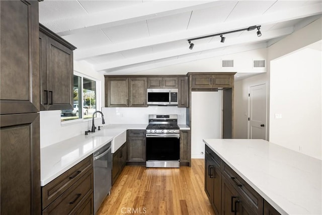 kitchen with stainless steel appliances, visible vents, a sink, and lofted ceiling with beams