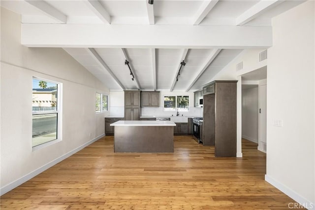 kitchen featuring a healthy amount of sunlight, light countertops, a kitchen island, and dark brown cabinetry