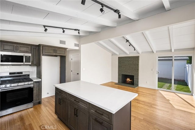 kitchen featuring visible vents, light countertops, lofted ceiling with beams, appliances with stainless steel finishes, and open floor plan