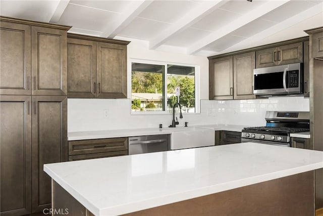 kitchen featuring vaulted ceiling with beams, tasteful backsplash, appliances with stainless steel finishes, a kitchen island, and dark brown cabinetry