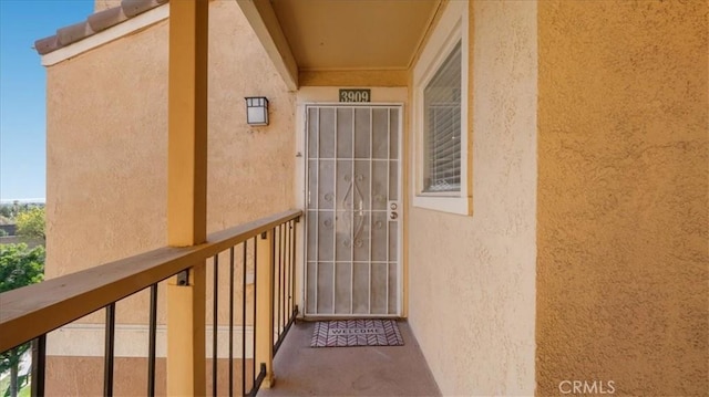 entrance to property with a balcony and stucco siding