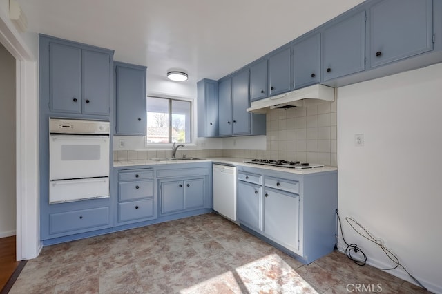 kitchen with under cabinet range hood, white appliances, a sink, light countertops, and a warming drawer