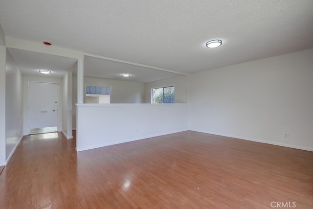 empty room featuring a textured ceiling, baseboards, and wood finished floors