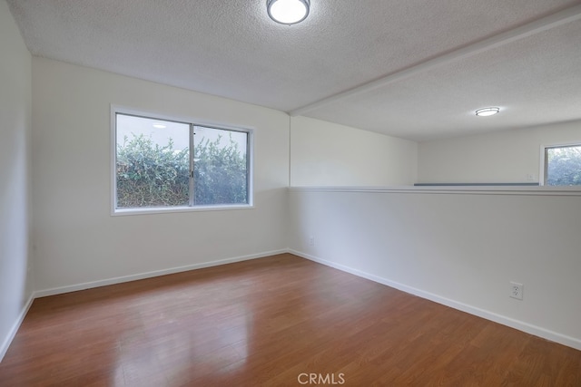 spare room featuring a textured ceiling, baseboards, and wood finished floors