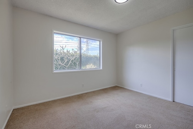 unfurnished bedroom with light carpet, a textured ceiling, and baseboards