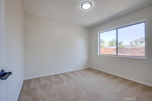 empty room with baseboards, a textured ceiling, and light colored carpet