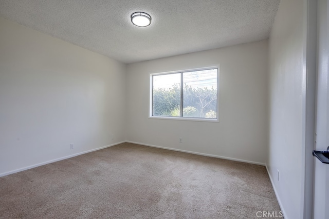 carpeted spare room featuring a textured ceiling and baseboards