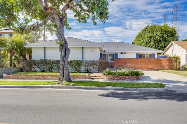 ranch-style home with concrete driveway, brick siding, and fence