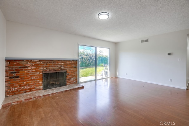 unfurnished living room featuring a fireplace, wood finished floors, visible vents, and baseboards