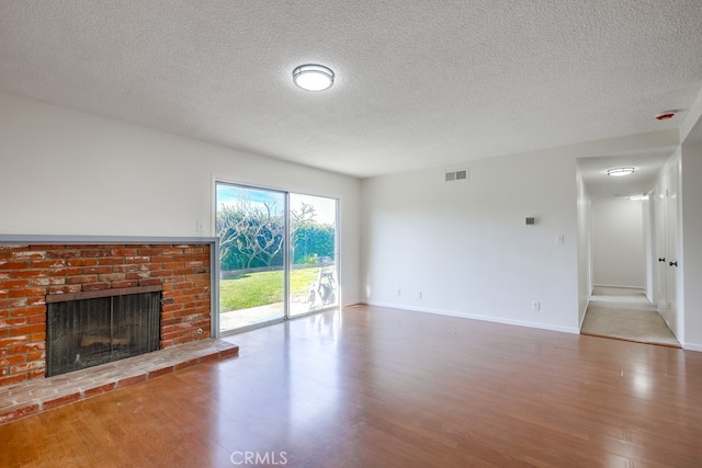 unfurnished living room with baseboards, a fireplace, visible vents, and wood finished floors