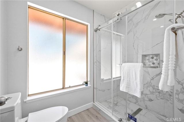 full bath featuring baseboards, toilet, a marble finish shower, and wood finished floors