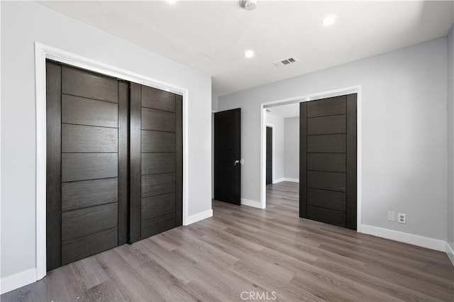 unfurnished bedroom featuring recessed lighting, wood finished floors, visible vents, baseboards, and a closet