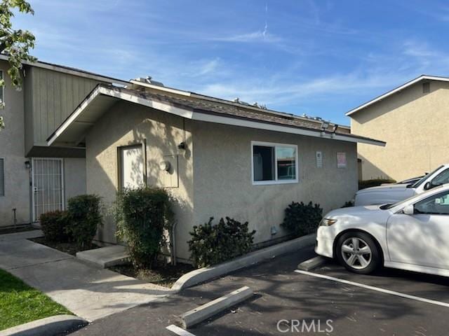 view of property exterior with uncovered parking and stucco siding