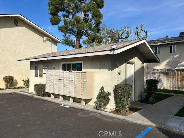 view of side of home featuring fence, mail area, and stucco siding