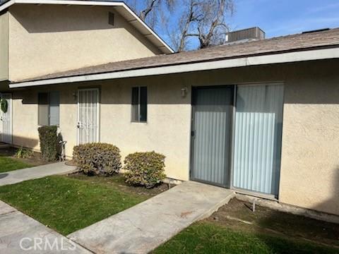 doorway to property featuring a lawn and stucco siding