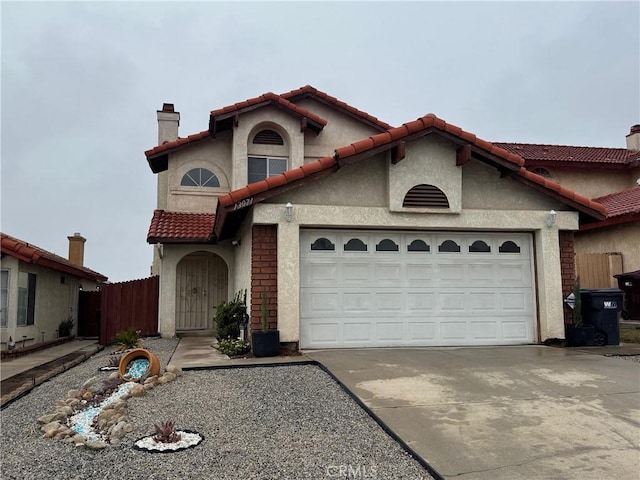 mediterranean / spanish-style house with a garage, a tile roof, concrete driveway, stucco siding, and a chimney