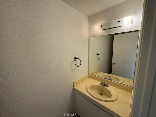 bathroom with a textured wall and vanity