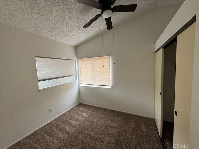 unfurnished bedroom featuring lofted ceiling, a textured ceiling, dark carpet, and a closet