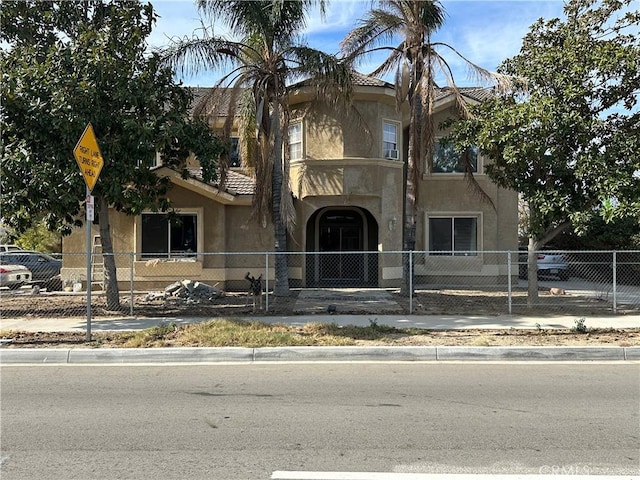 view of front of property featuring a fenced front yard, a tiled roof, and stucco siding