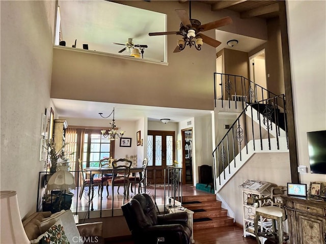 living room with stairway, wood finished floors, a high ceiling, french doors, and ceiling fan with notable chandelier