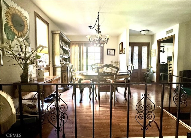 dining room featuring french doors, wood finished floors, visible vents, and a notable chandelier