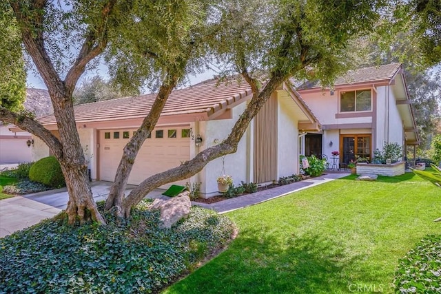 view of front of property with a tile roof, a front yard, stucco siding, a garage, and driveway