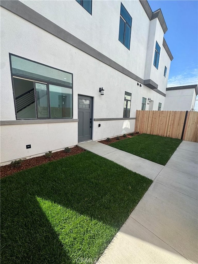 exterior space with a yard, fence, and stucco siding