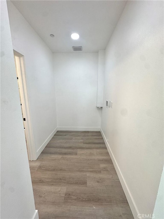 corridor with wood finished floors, visible vents, and baseboards