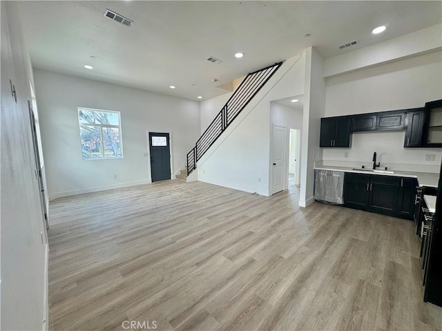 interior space with light wood finished floors, visible vents, light countertops, a sink, and dark cabinetry