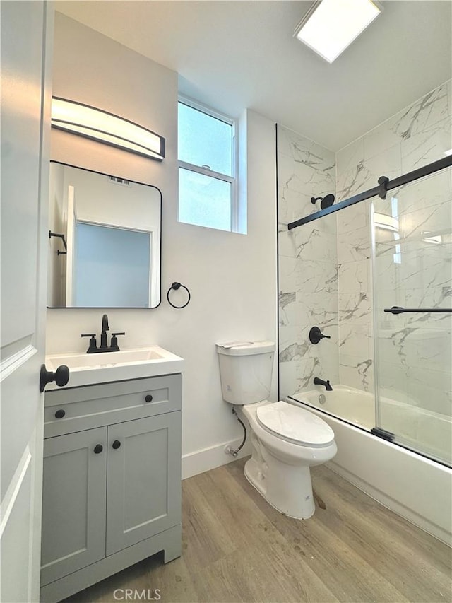 full bathroom featuring toilet, shower / bath combination with glass door, wood finished floors, vanity, and baseboards