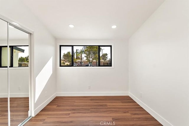 spare room with baseboards, wood finished floors, and recessed lighting