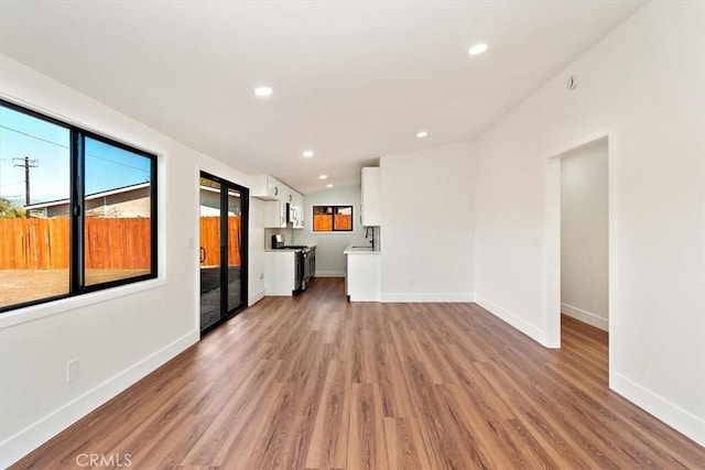 unfurnished living room featuring recessed lighting, wood finished floors, and baseboards