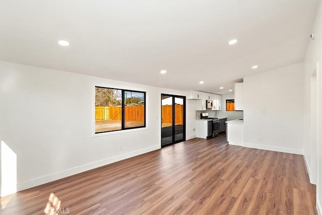 unfurnished living room with baseboards, wood finished floors, and recessed lighting