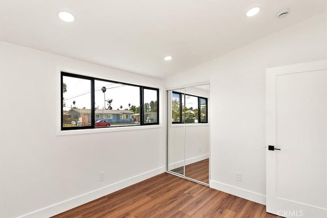 unfurnished bedroom with a closet, baseboards, wood finished floors, and recessed lighting