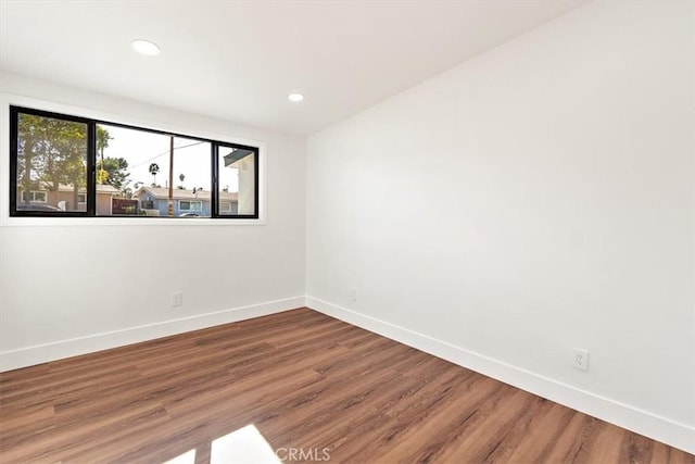 empty room with recessed lighting, wood finished floors, and baseboards