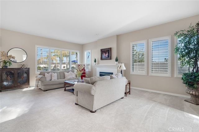 living room featuring plenty of natural light, baseboards, a fireplace, and light colored carpet